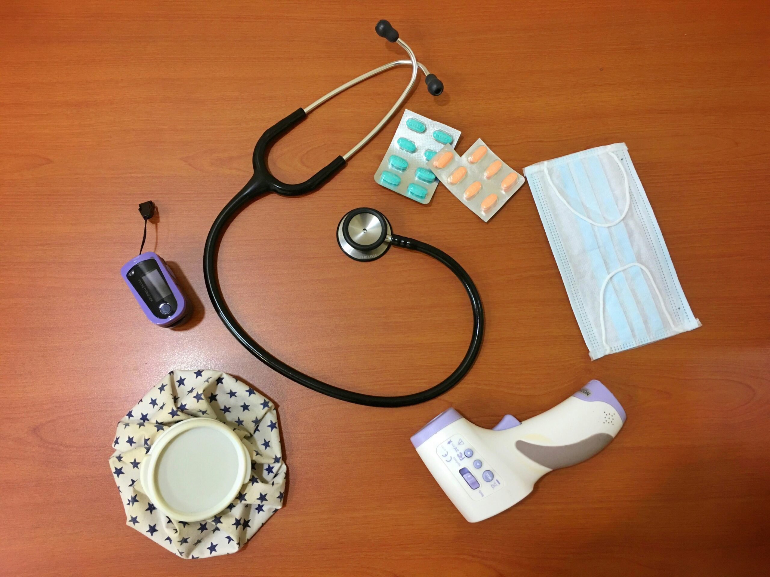 kristine-wook-kIZCzaf0jko-unsplash table with supplement blister packs, face mask, stethoscope, thermometer, heat pack